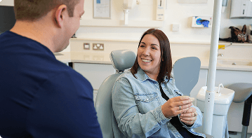 Dr Sean Roberts discussing facial aesthetics with a patient holding a mirror