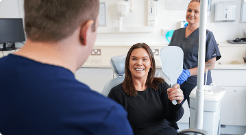 Dr Sean Roberts discussing general dental care with a patient holding a mirror